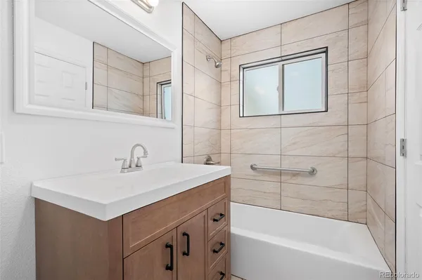 a bathroom with a sink vanity tub shower and a mirror