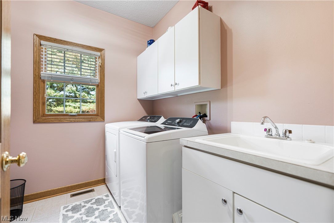 939 Pontius Road Mogadore, OH 44260 - Photo 17 of 35 Laundry room featuring washer and clothes dryer, cabinets, light tile floors, hookup for a washing machine, and sink