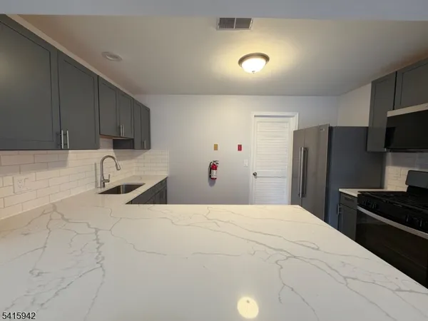 a large white kitchen with a sink stainless steel appliances and cabinets