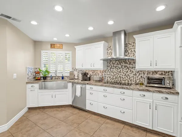 a kitchen with granite countertop white cabinets sink and stainless steel appliances