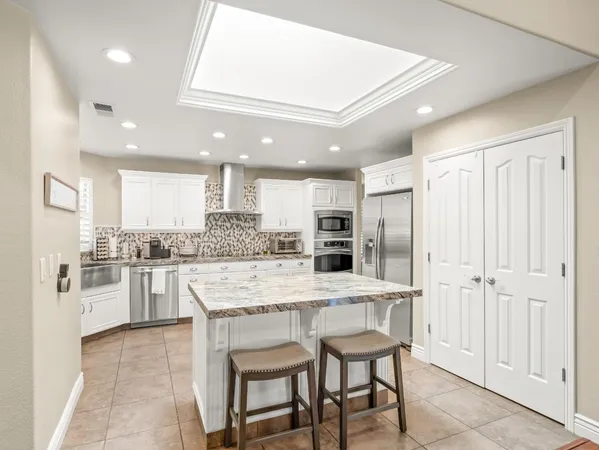 a kitchen with stainless steel appliances kitchen island granite countertop a refrigerator and a stove top oven