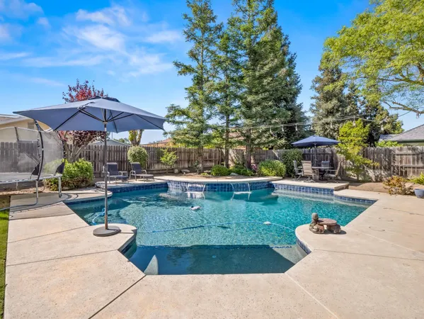 a view of pool with umbrella and trees around