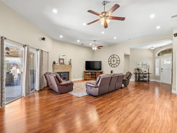 a living room with furniture kitchen view and a wooden floor