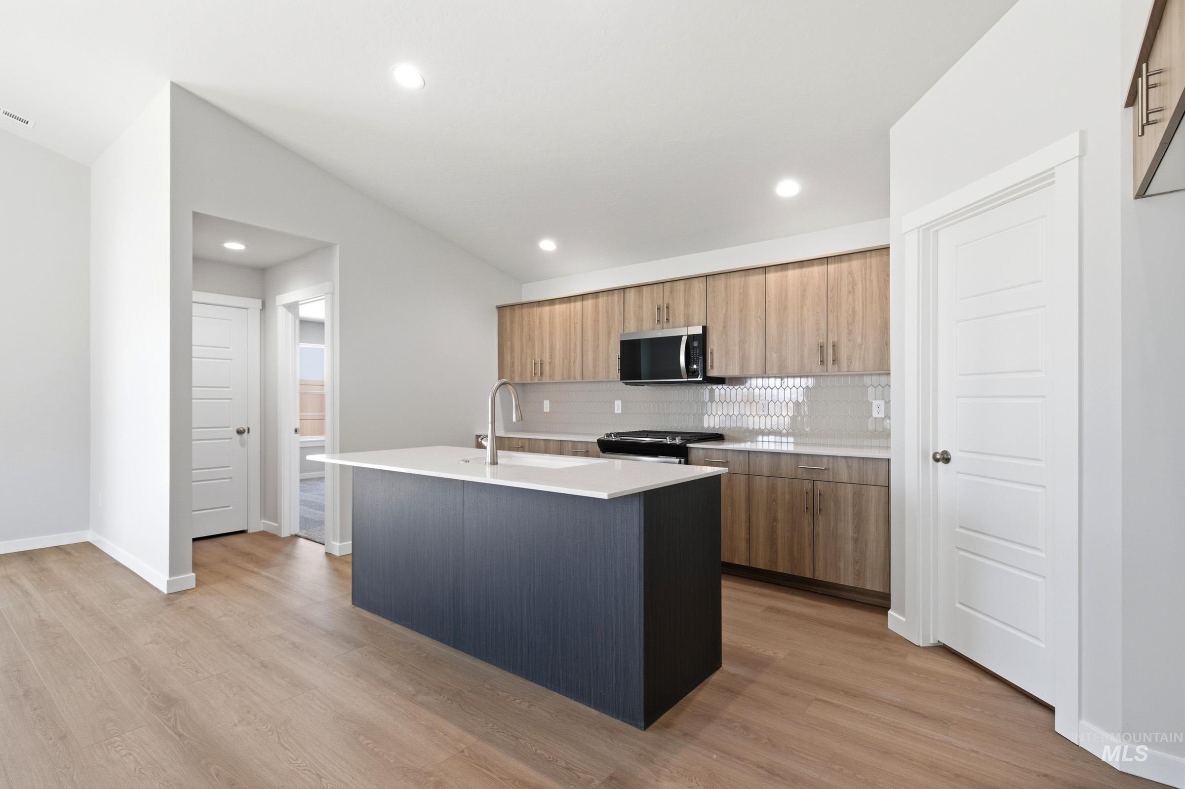 1184 West Jasper Street Meridian, ID 83642 - Photo 4 of 18 Open-concept kitchen featuring a dark-toned island with an undermount sink, a gooseneck faucet, and light countertops