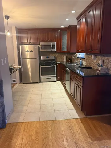 a kitchen with granite countertop a refrigerator and a stove top oven
