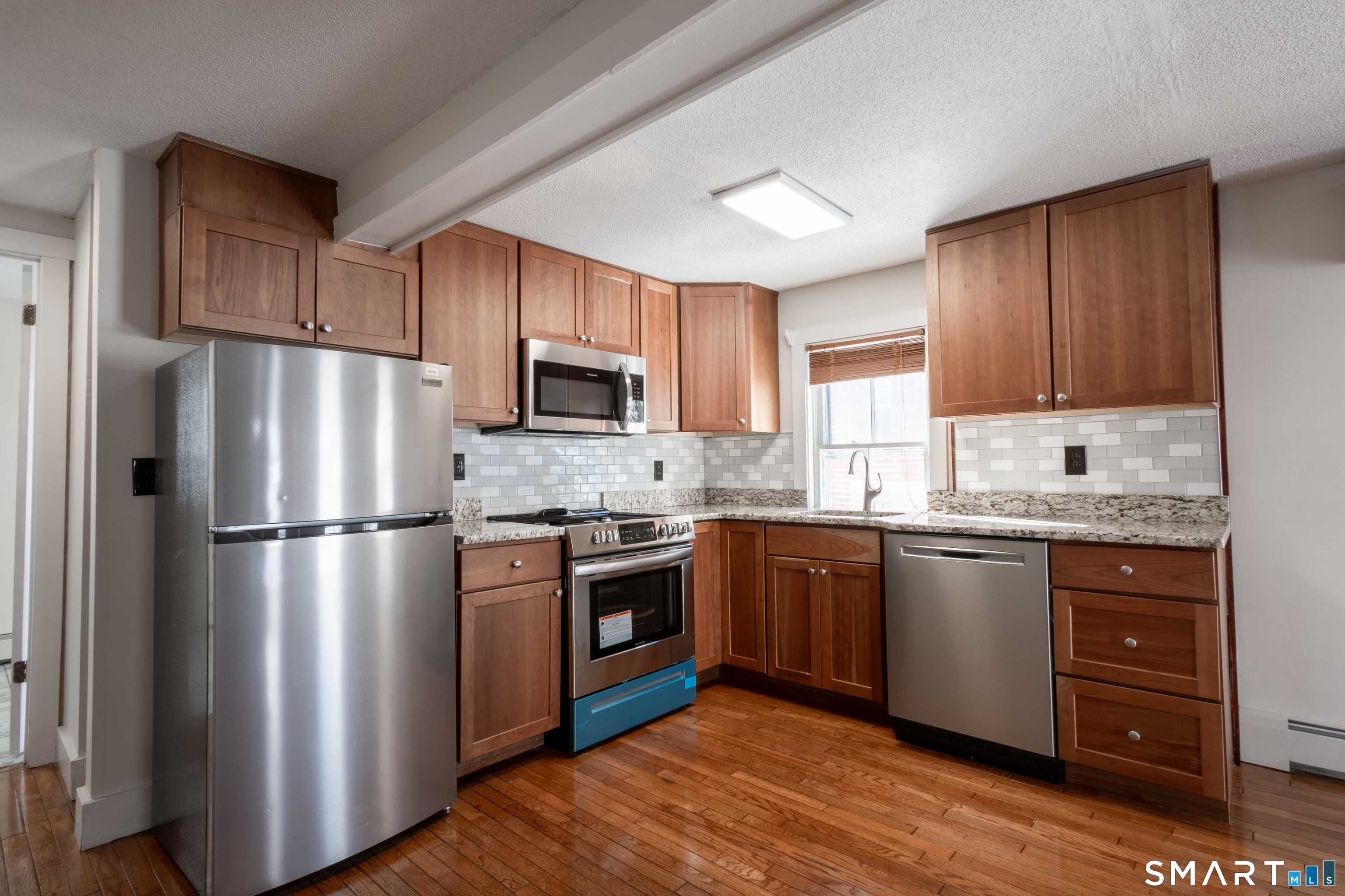 89 Hempstead Street New London, CT 06320 - Photo 3 of 14 a kitchen with granite countertop stainless steel appliances and wooden cabinets