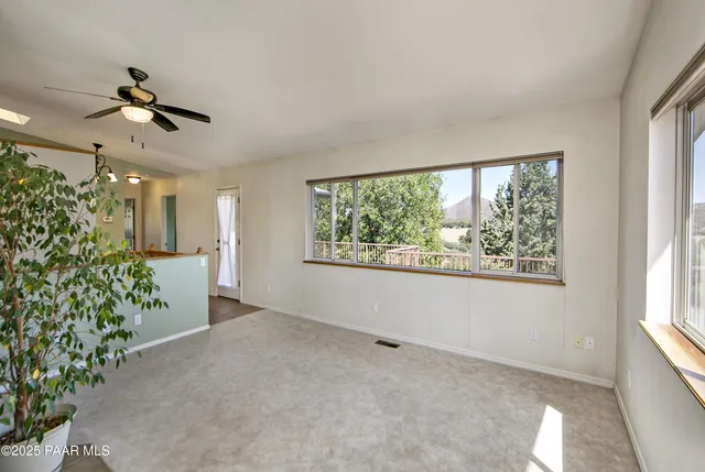 an empty room with windows and ceiling fan