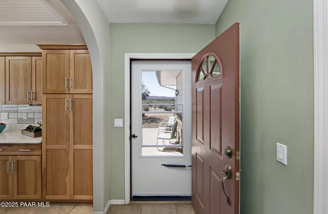 an empty room that has a window and a chandelier fan