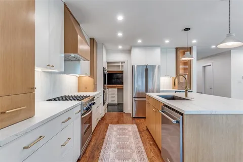 a large kitchen with stainless steel appliances granite countertop a lot of counter space and wooden floors