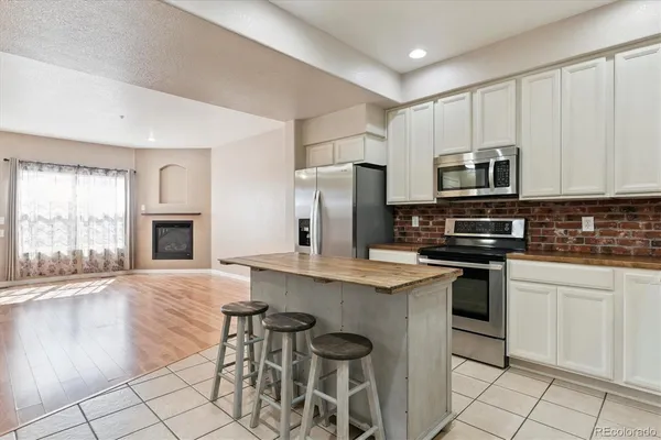 a kitchen with stainless steel appliances granite countertop a stove top oven a sink dishwasher a refrigerator and white cabinets with wooden floor