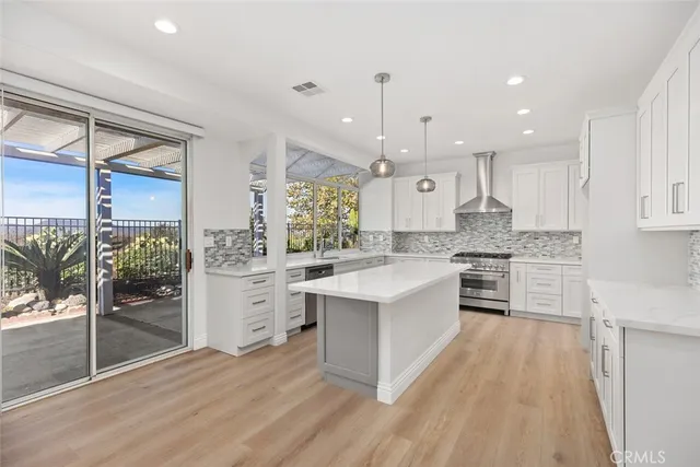 a large kitchen with kitchen island a counter top space a sink stainless steel appliances and cabinets