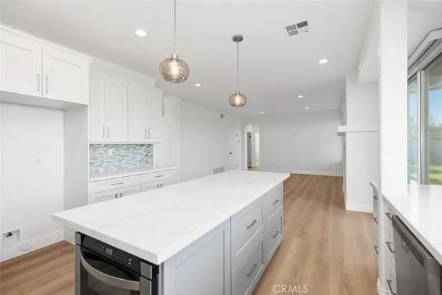 a large kitchen with a stove a sink dishwasher and a refrigerator with wooden floor