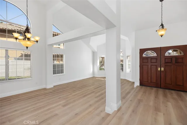 a view of an empty room with wooden floor and windows