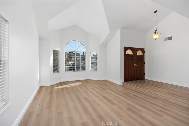 an empty room with wooden floor cabinet and windows