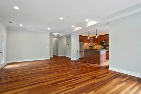 a view of kitchen with kitchen island granite countertop wooden floor and stainless steel appliances