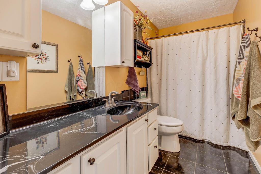 1300 Hubbard Road Galloway, OH 43119 - Photo 44 of 89 • Ceramic tile flooring • Burnt orange painted walls • Enclosed vanity with single bowl, cultured marble sinktop • Three-bulb wall light • (2) Wall cabinets • Tub/shower combination with ceramic tile surround • Ceiling exhaust