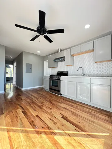 a kitchen with stainless steel appliances granite countertop a sink cabinets and wooden floor