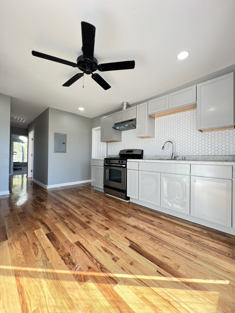 3343 West 59th Place, Unit 2 Chicago, IL 60629 - Photo 8 of 10 a kitchen with stainless steel appliances granite countertop a sink cabinets and wooden floor