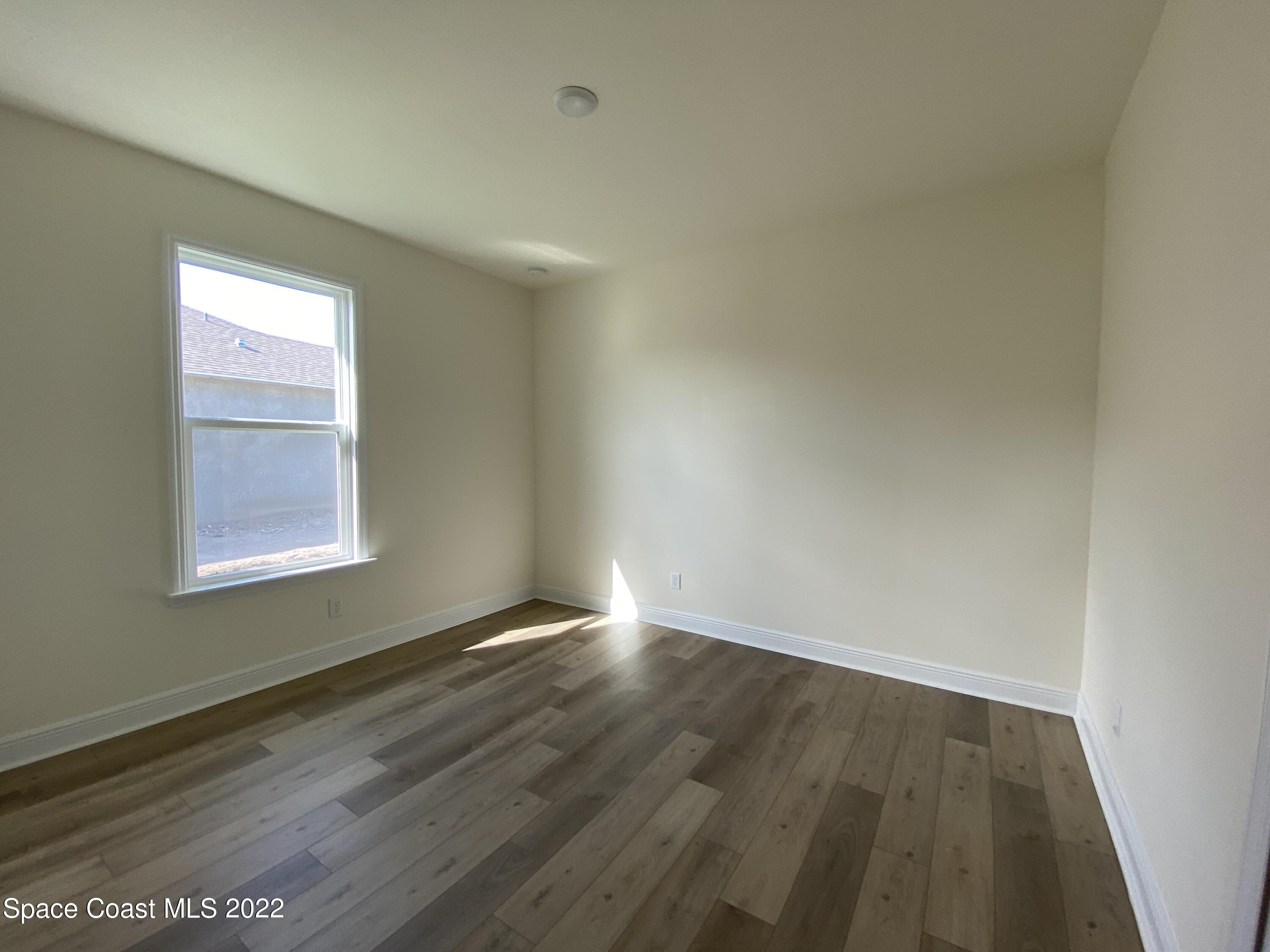 1493 Killian Drive Palm Bay, FL 32905 - Photo 14 of 20 an empty room with wooden floor and windows