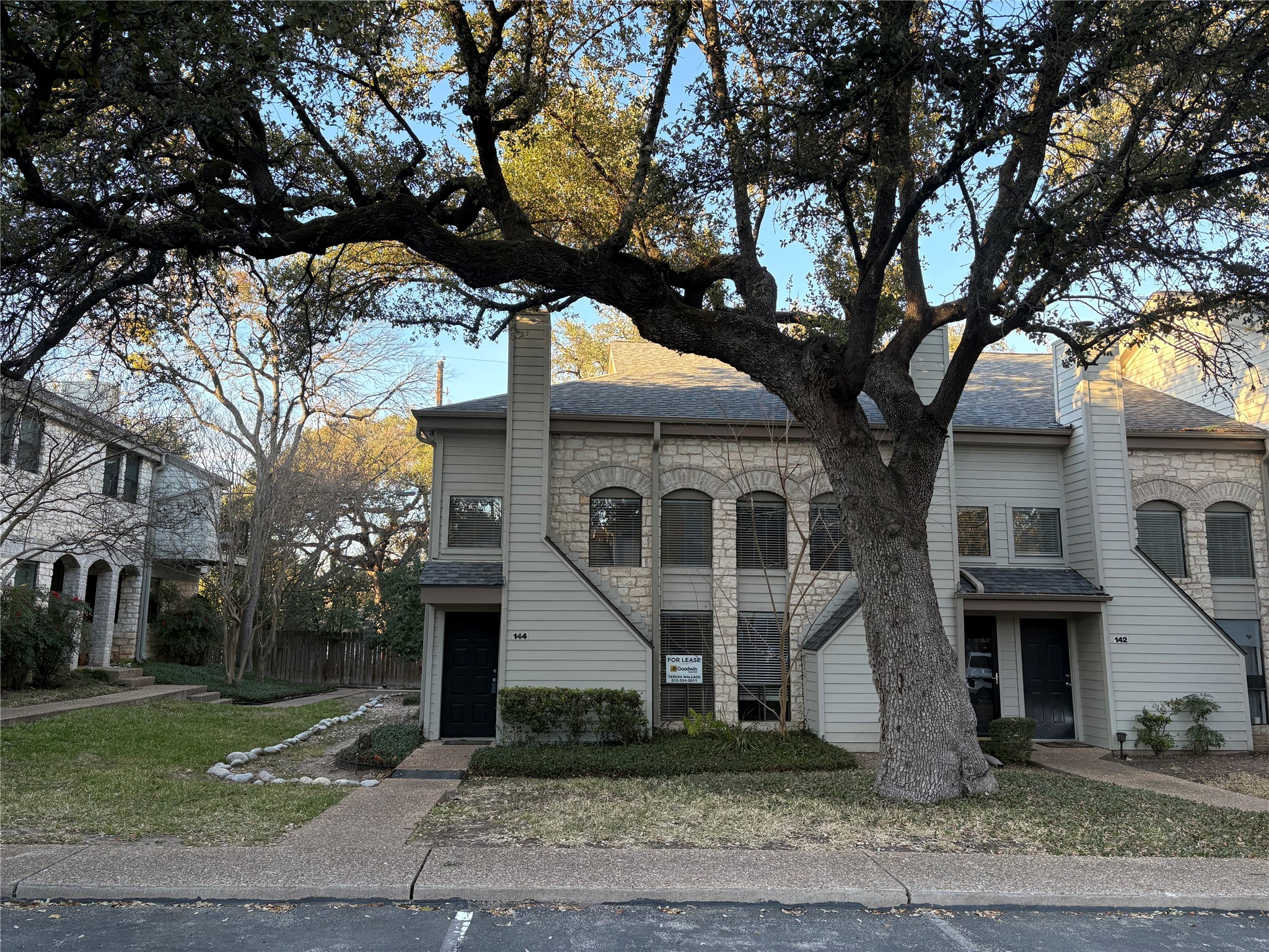 9226 Jollyville Road, Unit 144 Austin, TX 78759 - Photo 2 of 40 View of front of home featuring stone siding, a chimney, a shingled roof, and a front lawn