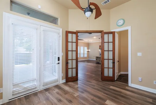 an empty room with wooden floor mirror and windows