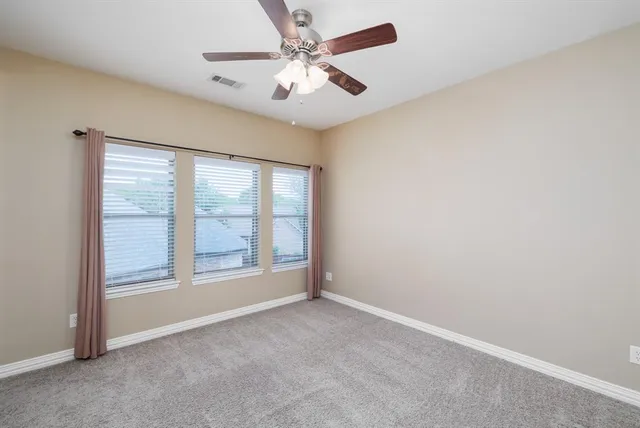 an empty room with chandelier fan and windows