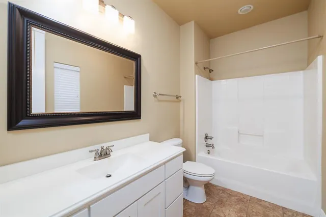 a bathroom with a toilet a sink a tub and a mirror