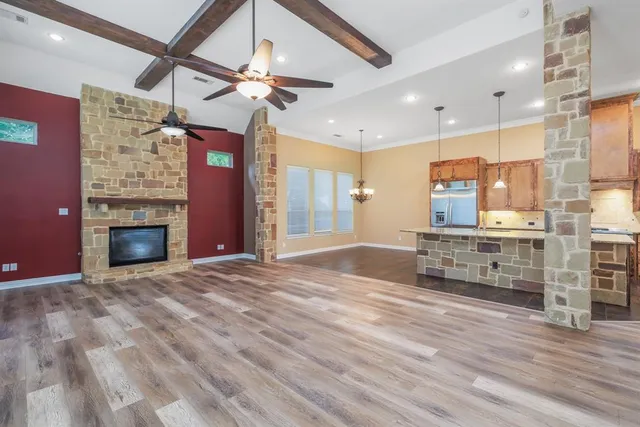 a view of an empty room with a fireplace and a ceiling fan