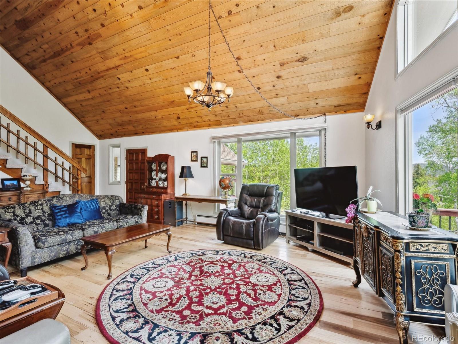 9390 South Warhawk Road Conifer, CO 80433 - Photo 16 of 46 a living room with furniture a flat screen tv and a floor to ceiling window