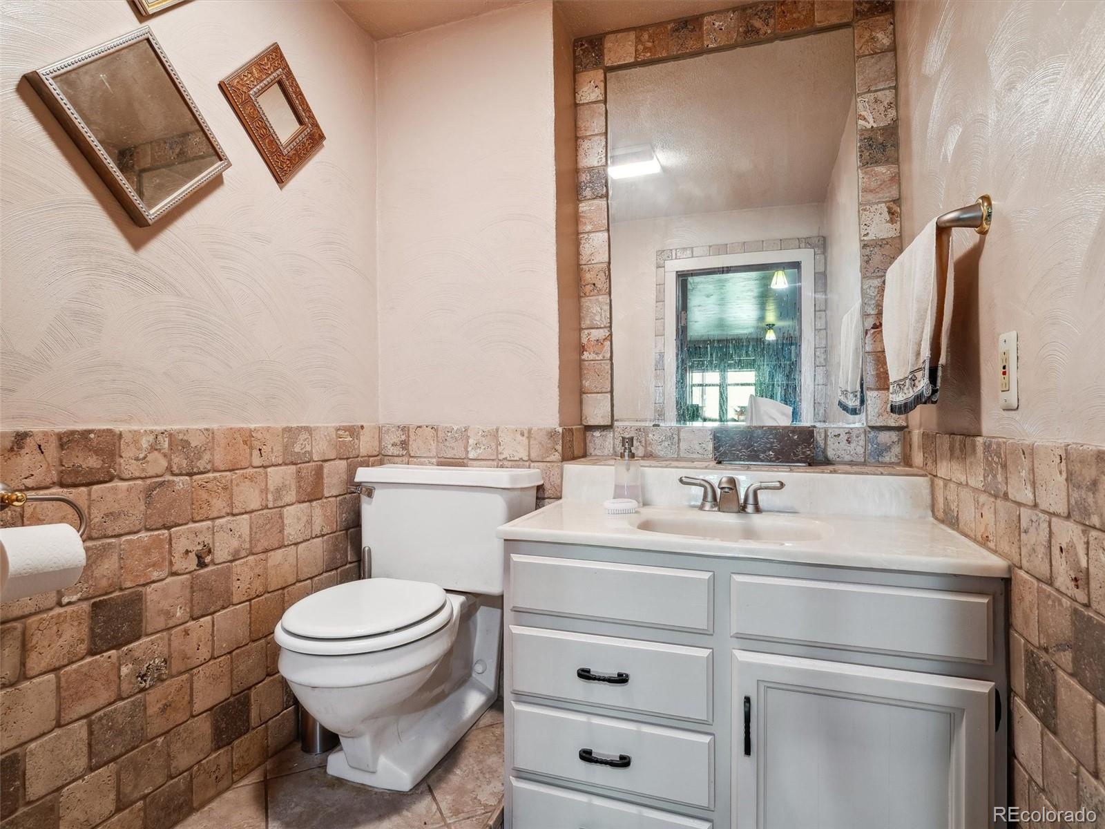 9390 South Warhawk Road Conifer, CO 80433 - Photo 29 of 46 a bathroom with a toilet sink vanity and mirror