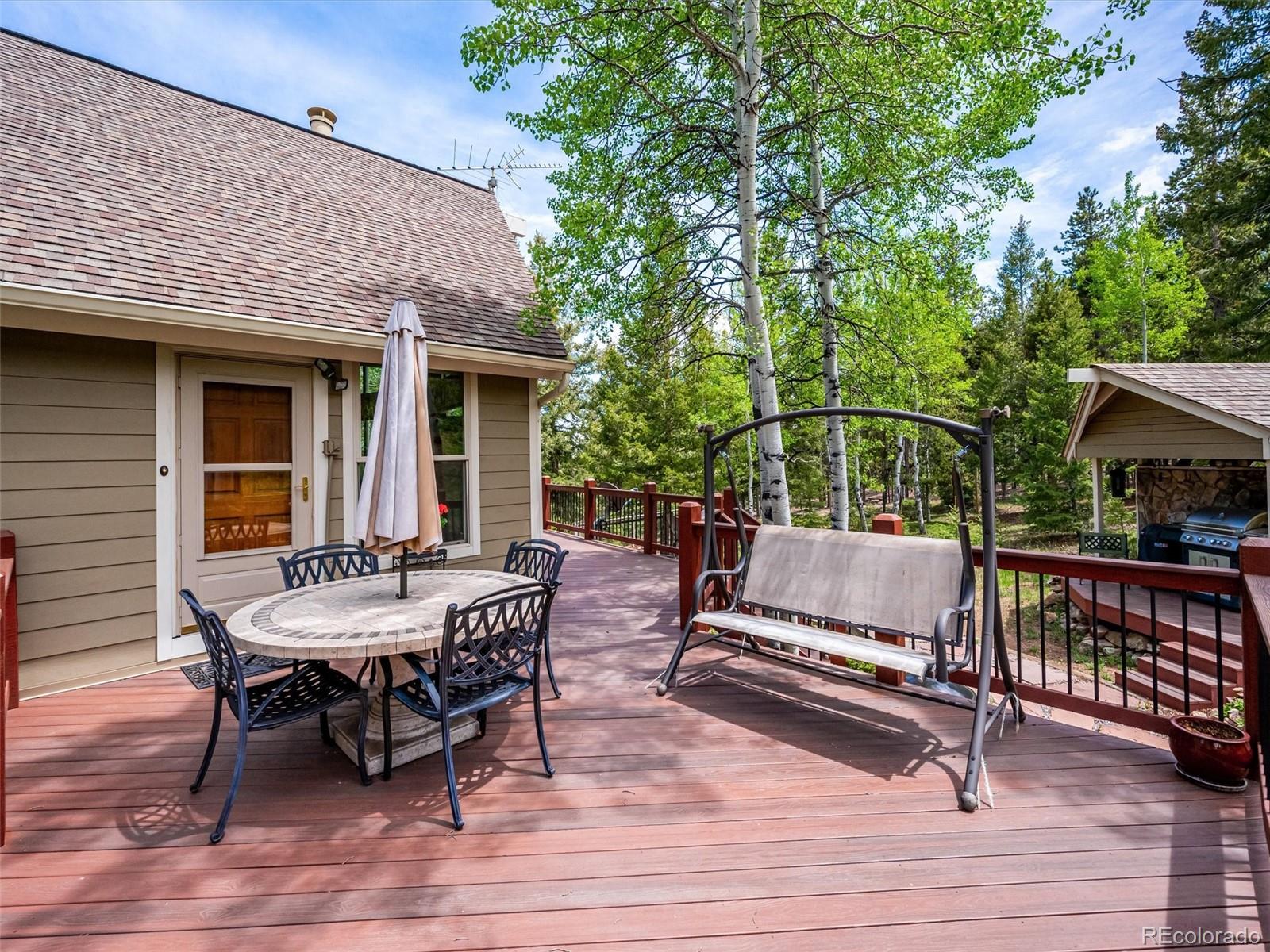 9390 South Warhawk Road Conifer, CO 80433 - Photo 30 of 46 a view of a roof deck with table and chairs couches with wooden floor and fence