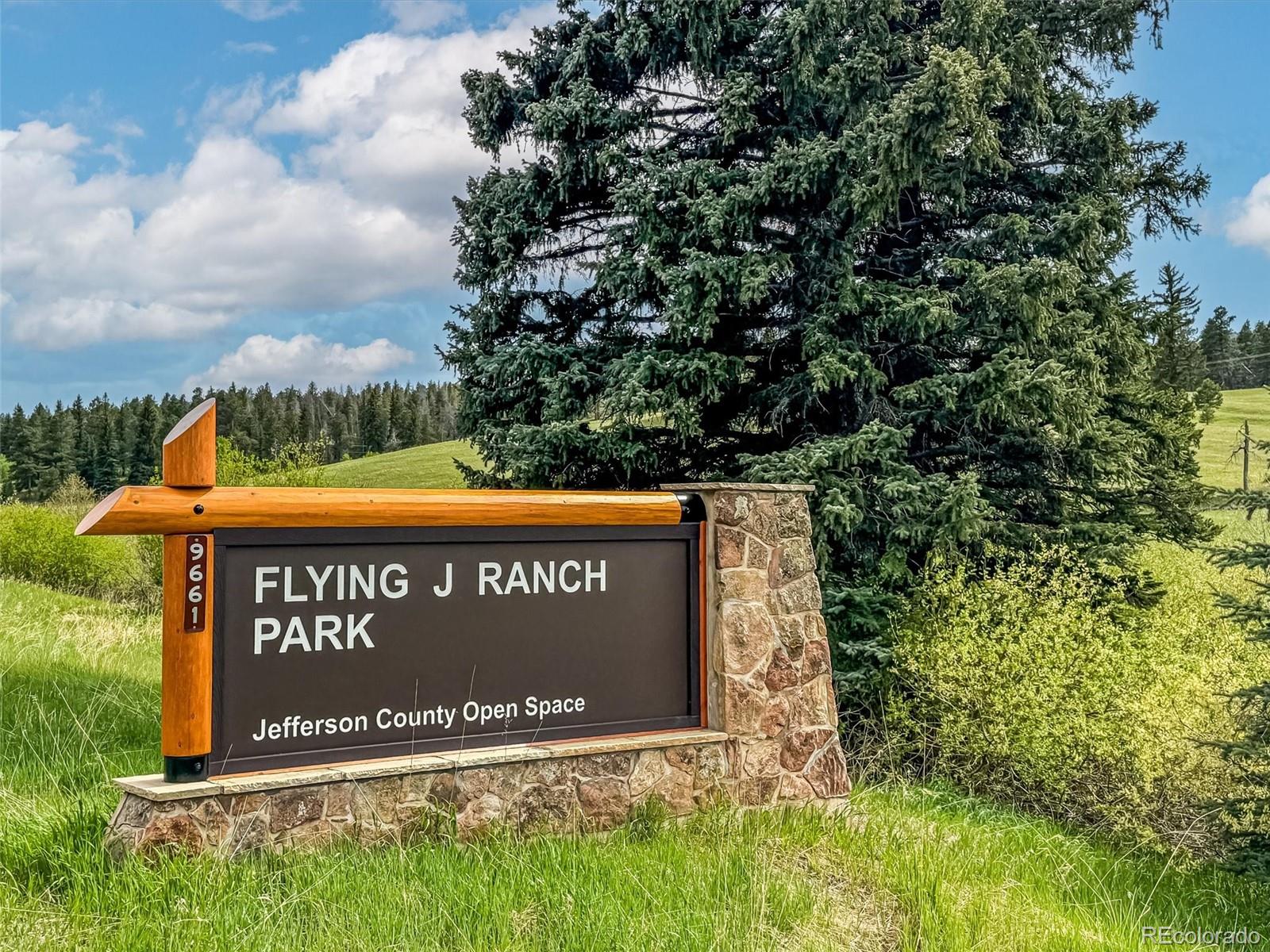 9390 South Warhawk Road Conifer, CO 80433 - Photo 43 of 46 a sign that is sitting on a brick wall with plants and trees