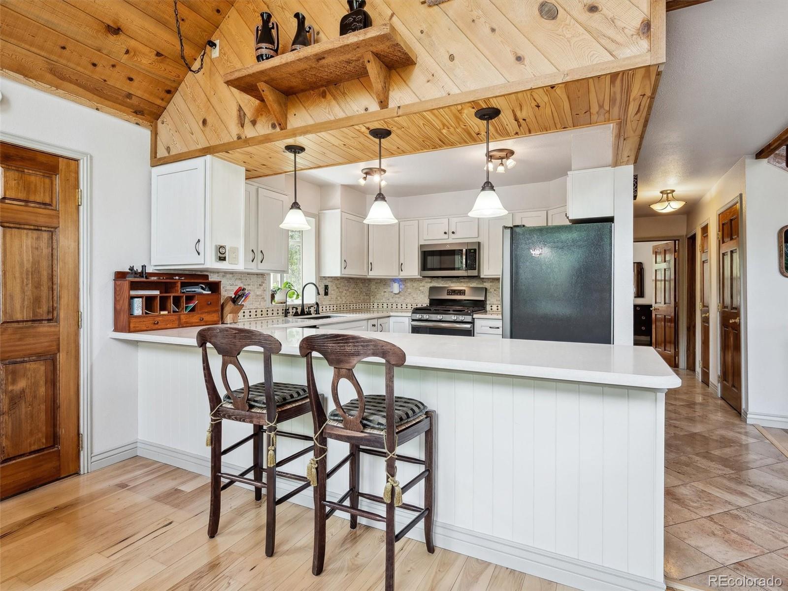 9390 South Warhawk Road Conifer, CO 80433 - Photo 9 of 46 a kitchen with stainless steel appliances kitchen island granite countertop a table chairs and a refrigerator