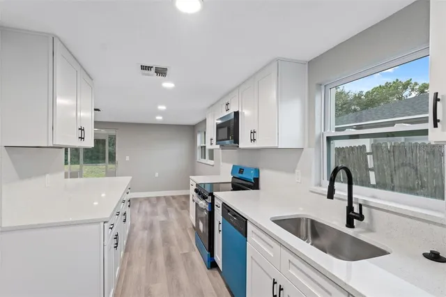 a kitchen with a sink a counter top space stainless steel appliances a window and a cabinets