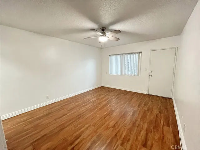 an empty room with wooden floor ceiling fan and windows
