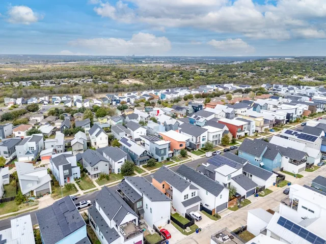 an aerial view of a city with lots of residential buildings and ocean view in back