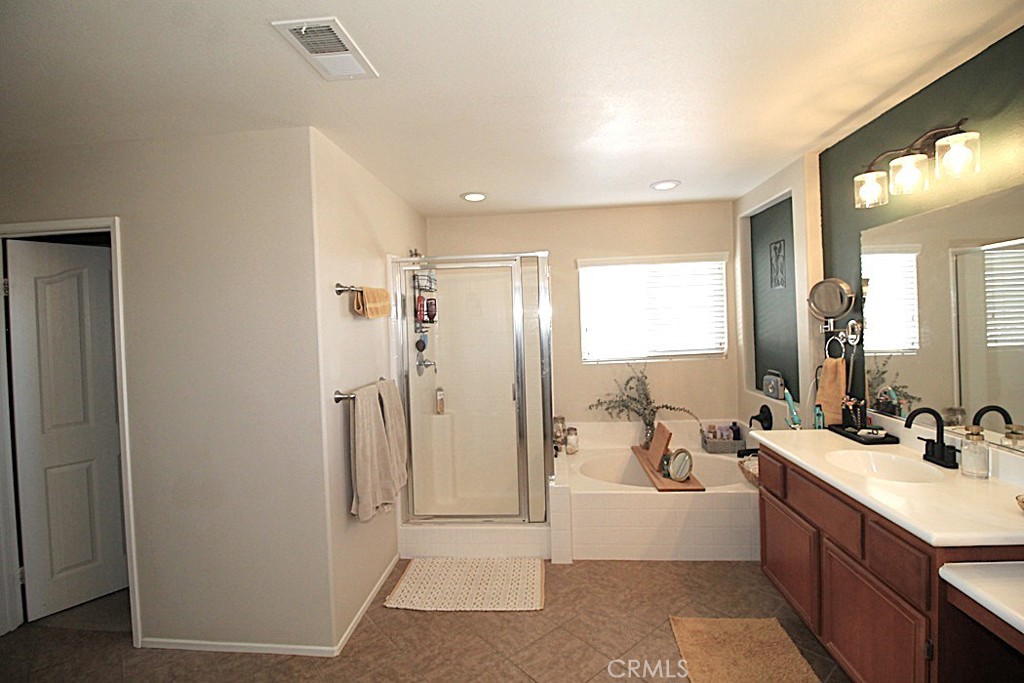 924 Condor Street Barstow, CA 92311 - Photo 39 of 52 a bathroom with a double vanity sink a mirror a shower and a bathtub