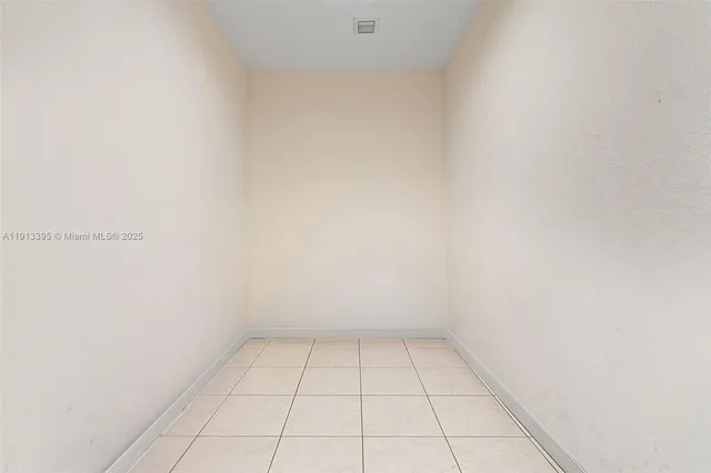 a view of yellow house with a yard and potted plants