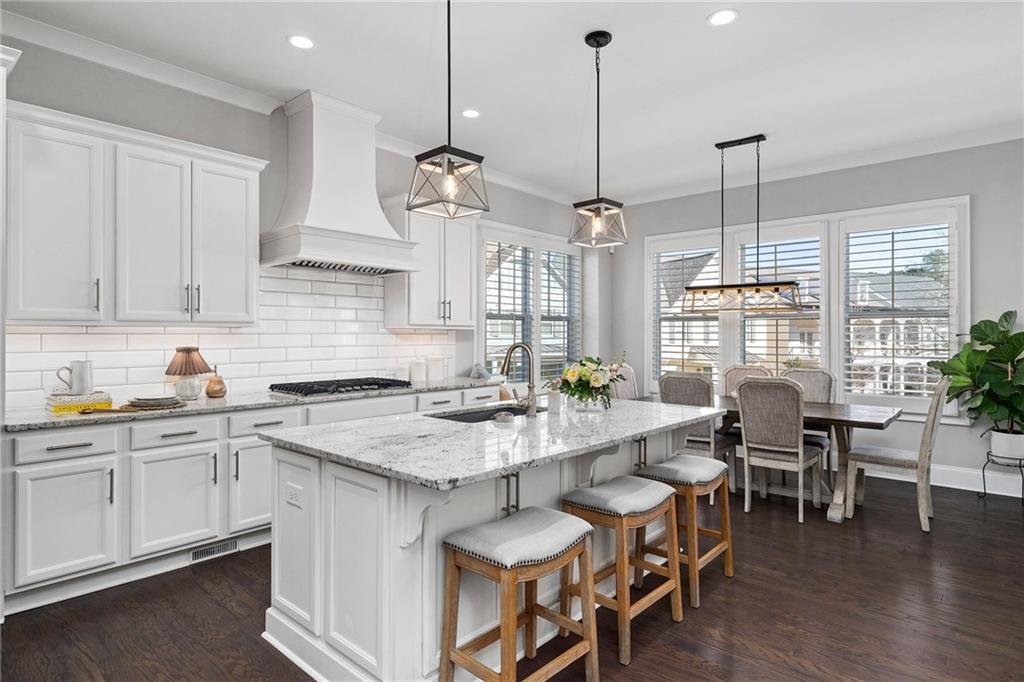 165 Rowan Avenue Alpharetta, GA 30009 - Photo 18 of 84 a kitchen with stainless steel appliances granite countertop a stove a sink a dining table chairs and white cabinets next to a window