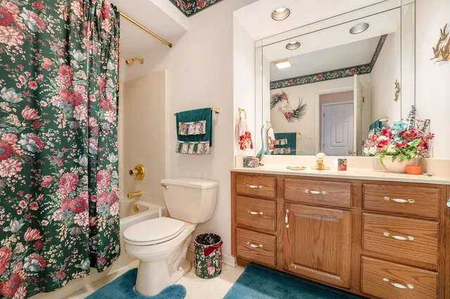 a bathroom with a toilet sink vanity granite and mirror