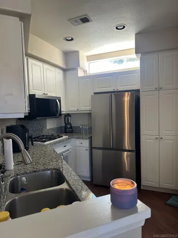a kitchen with a refrigerator sink and cabinets