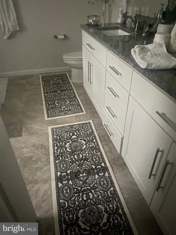a bathroom with a granite countertop sink a toilet and a mirror