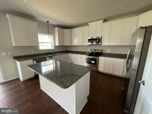 a kitchen with stainless steel appliances granite countertop a sink a stove a refrigerator a microwave and cabinets