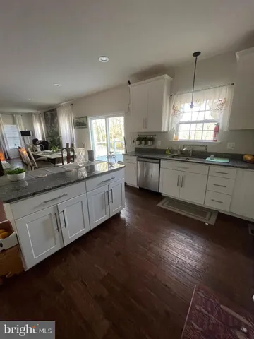 a kitchen with granite countertop white cabinets a sink and dishwasher