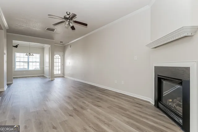a view of an empty room with a fireplace and wooden floor