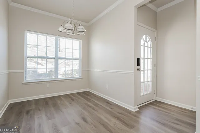 an empty room with wooden floor cabinet and windows
