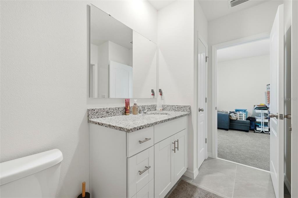 1503 Isleta Loop Kissimmee, FL 34741 - Photo 35 of 50 a bathroom with a granite countertop sink a toilet and a mirror