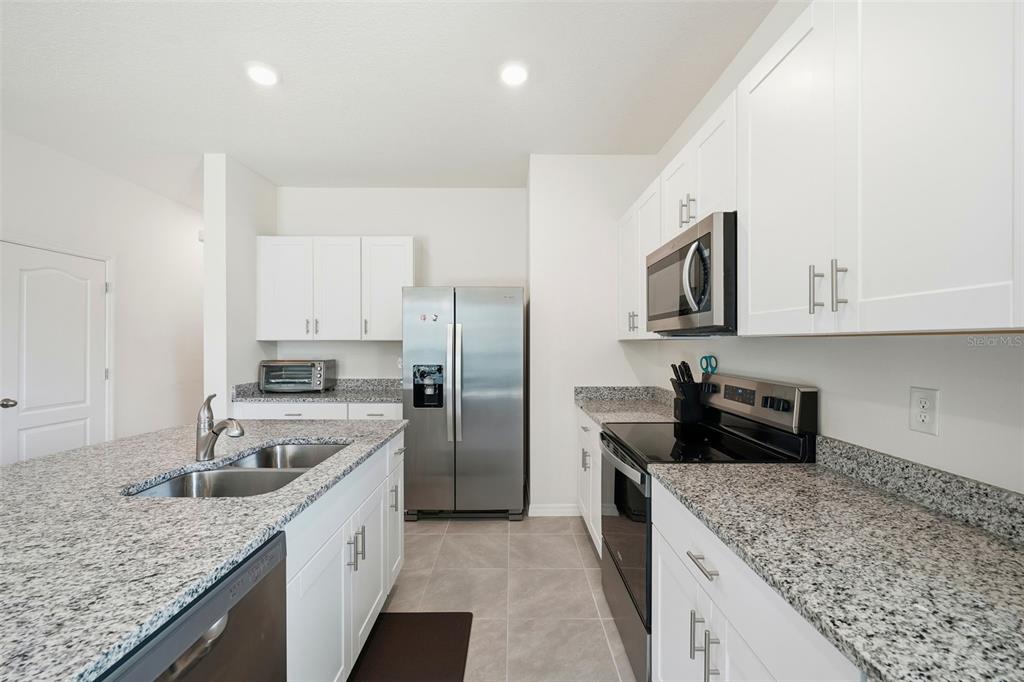 1503 Isleta Loop Kissimmee, FL 34741 - Photo 10 of 50 a kitchen with stainless steel appliances granite countertop a sink stove and refrigerator