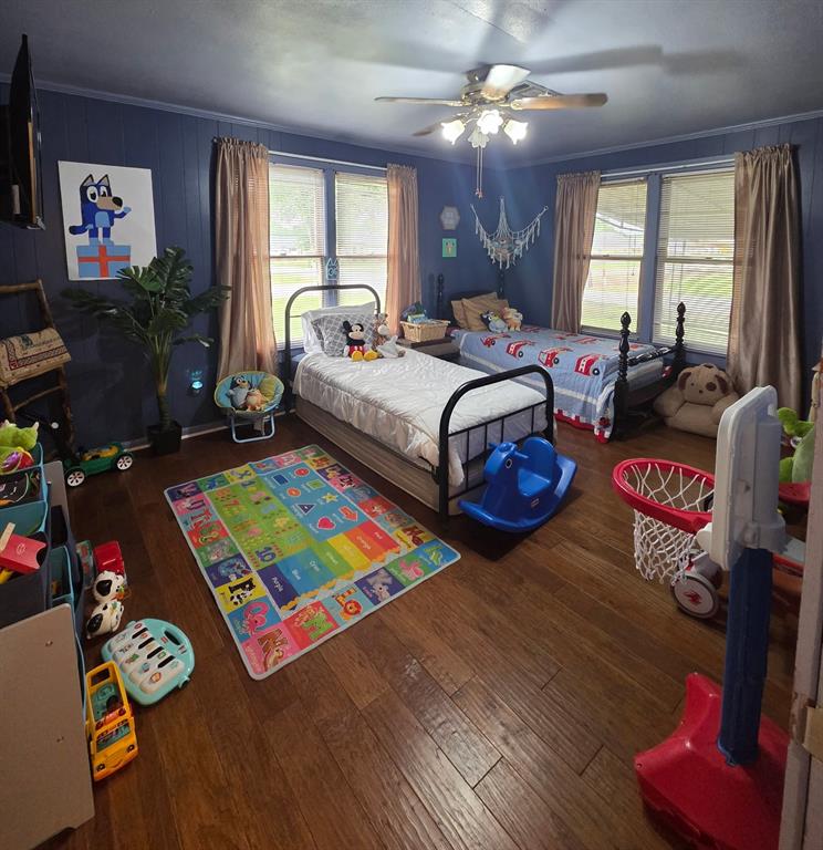 301 Old Plain Dealing Road Benton, LA 71006 - Photo 18 of 19 Spacious room featuring wood-finish flooring, two large windows with blinds and drapes, a ceiling fan with integrated lighting, and paneled walls