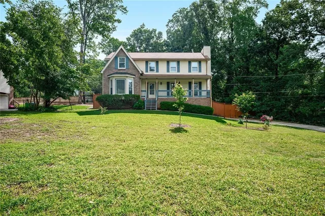 a front view of a house with garden and trees